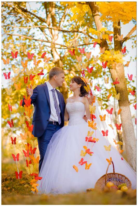 Под осенним деревом, декорированным подвесными гирляндами в виде желтых и красных бабочек, стоят жених невеста - фото 3105271 Видео-фотостудия "Svetlana & Evgenij"