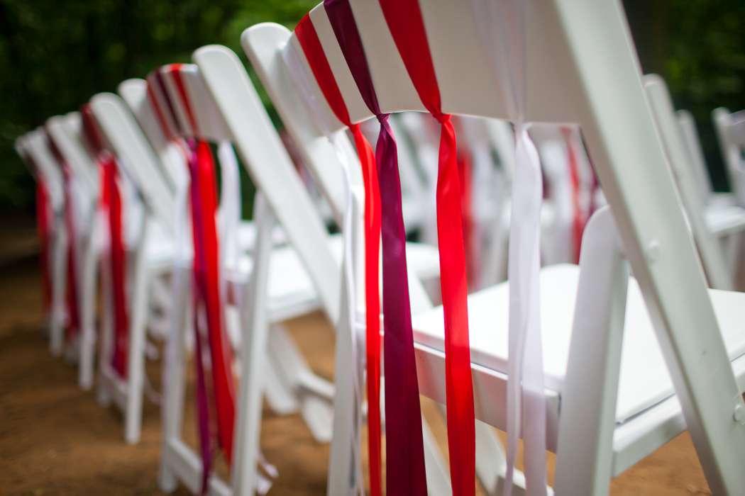 Стулья для гостей на выездной церемонии, украшенные  лентами в красных тонах - фото 2251098 Свадебное агентство "C and C"