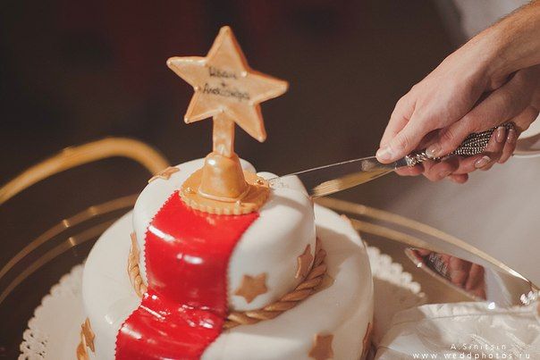 Невеста с женихом, разрезающие свадебный торт в белой мастике, украшенный красной дорожкой и золотой звездой  - фото 1055761 Свадебный распорядитель Мария Корецкая