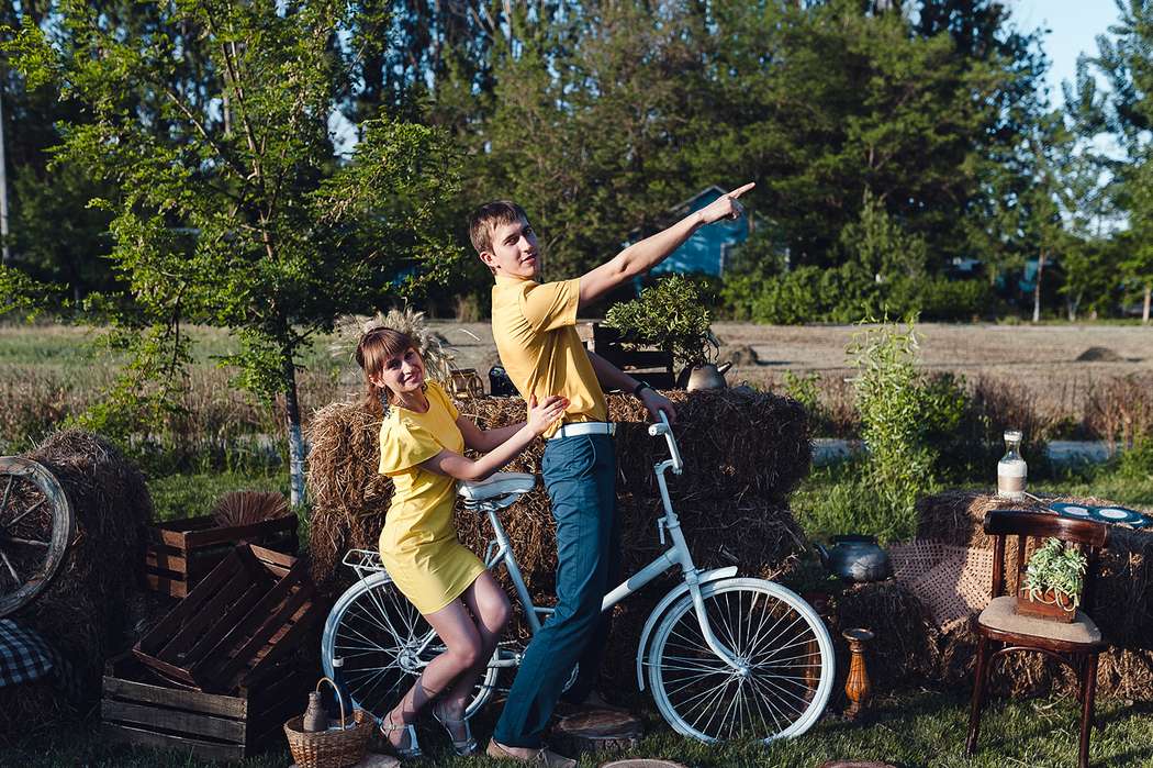 Парень с девушкой сидят на велосипеде на газоне, декорированном в рустикальном стиле, парень в желтой рубашке с джинсами, девушка - фото 2703208 PollyScratchcat