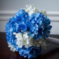 Букет невесты в круглом стиле из синих и белых гортензий, декорированный белой лентой 