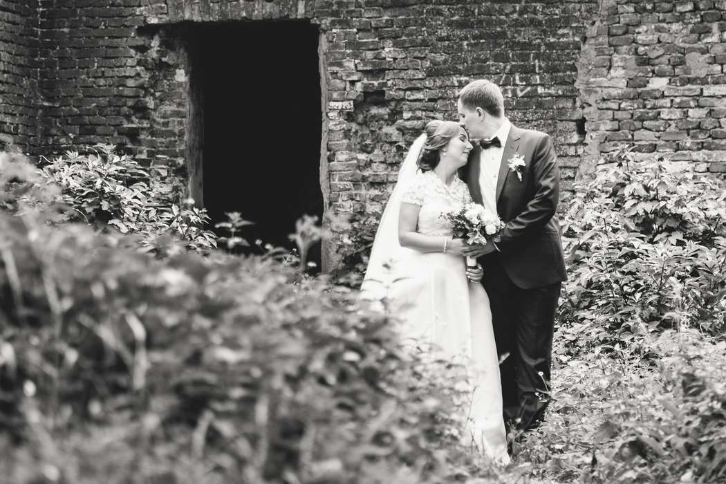 Жених и невеста, прислонившись друг к другу, стоят на фоне старого здания - фото 3547225 ikoda
