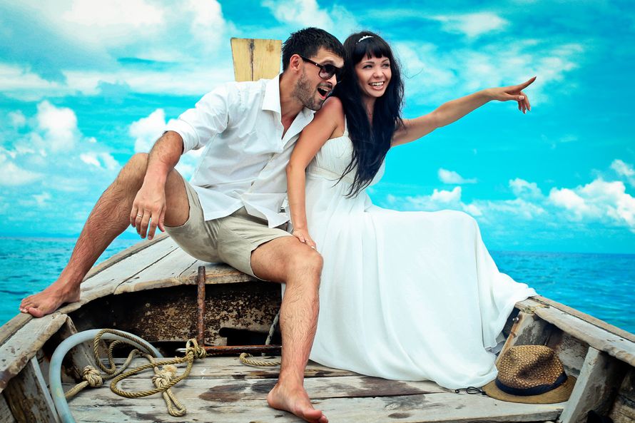 В лодке сидит парень в белой рубашке и бежевых шортах, обняв за талию невесту в открытом белом платье, которая указывает ему вдаль - фото 3291199 Dave Primov - protographer