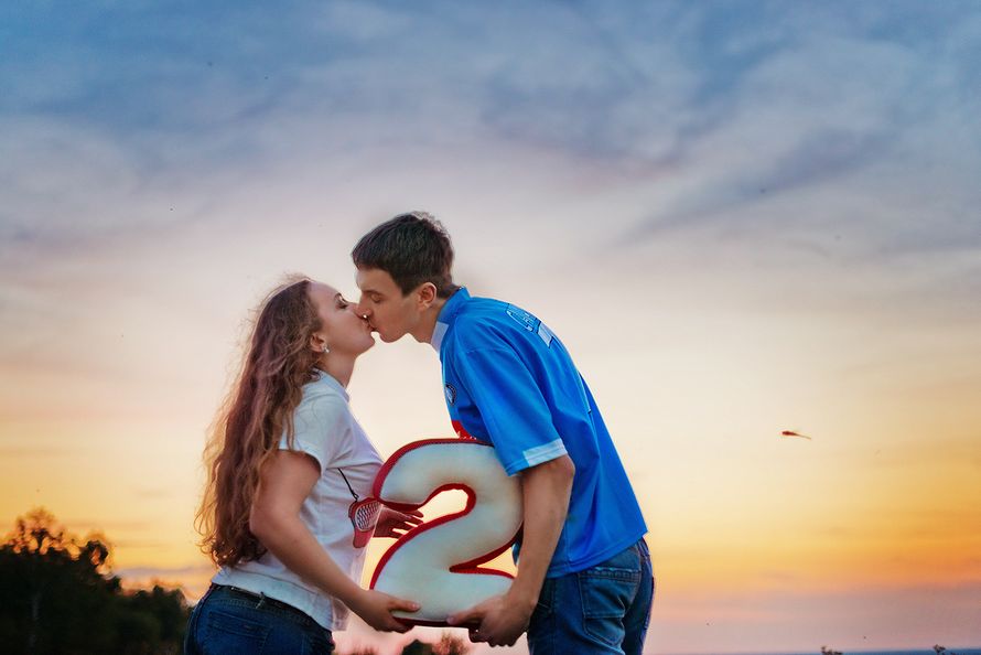 Пара целуется на фоне облачного неба и держат в руках большую цифру 2 - фото 3406255 Марина Романченко