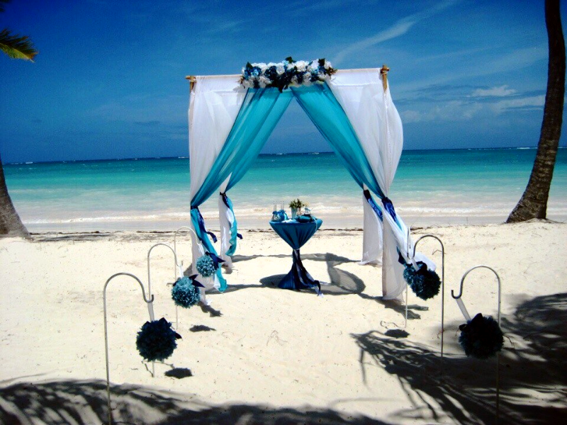 На пляже на фоне лазурного океана стоит свадебный шатер, украшенный голубой и белой газовой тканью и цветами, внутри столик для - фото 2477467 Wedding in Dominicana - свадьбы в Доминикане  