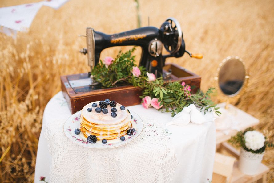 На белом стоике стоит старая ручная швейная машинка, тарелка с блинчиками и лежит композиция из листьев и цветов  - фото 2827173 Мяtа - цветы и декор