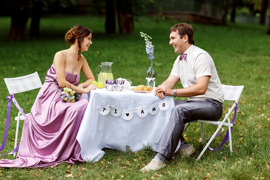 невеста, в сиреневом платье, сидит рядом с женихом, за белим столиком на природе, со стола свисает гирлянда с надписью черными - фото 3461039 Невеста01