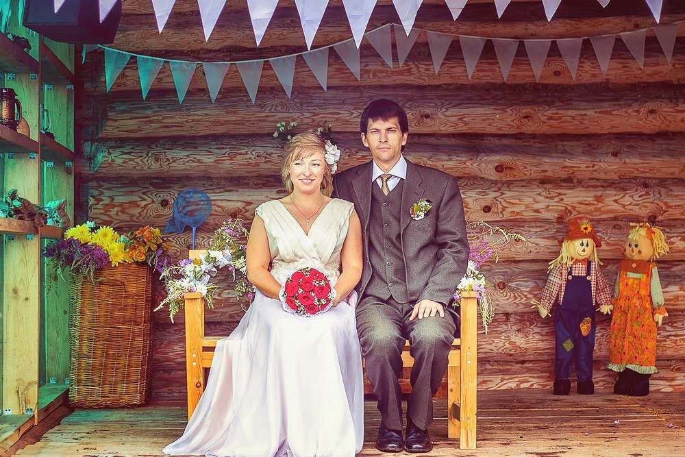 На фоне деревянной стены, на скамье под голубой гирляндой сидят жених и невеста - фото 2799039 Арт-группа Reverence - фотография