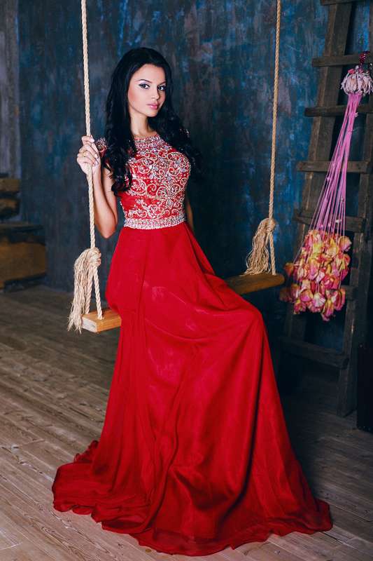 Подружка невесты в длинном красном платье с расклешенным низом, приталенным расшитым лифом без рукава, сидит на качелях  - фото 3340267 Amici di fiori - флористы