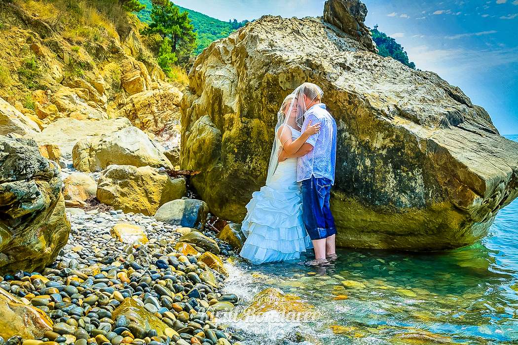 На пляже стоят жених с невестой, прикрывшись фатой, он в голубой рубашке и синих брюках, она в пышном, белом платье - фото 3438365 Свадебный фотограф Кирилл Бондарев