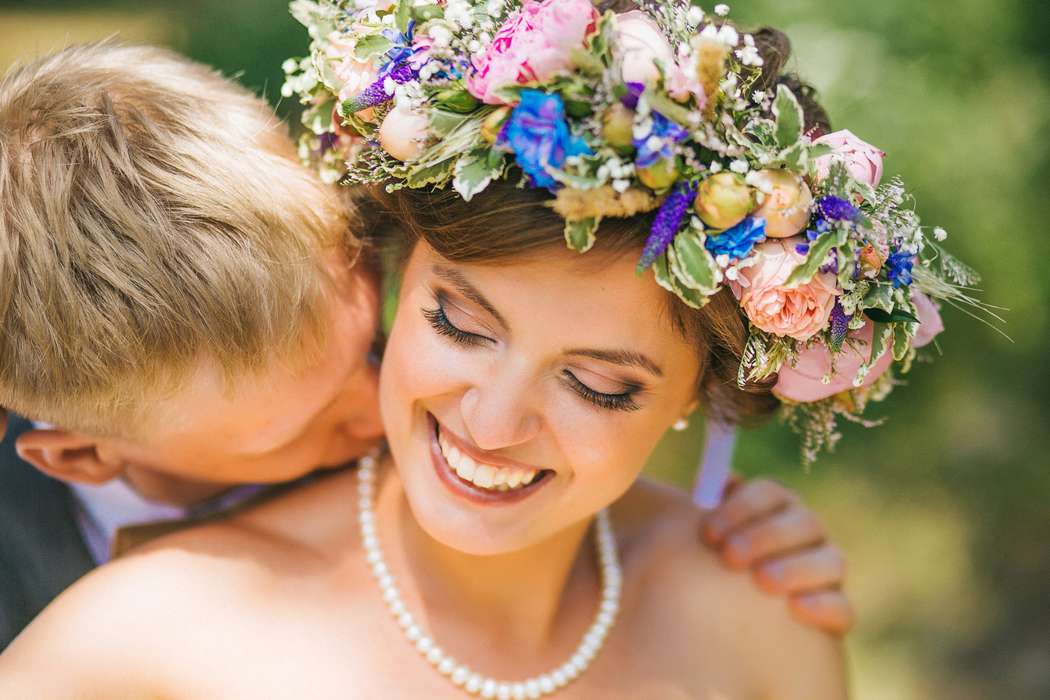 На голове невесты пышный венок из зелени, роз и синих цветов, шею украсили жемчужные бусы - фото 2155288 Фотограф Анна Евграфова