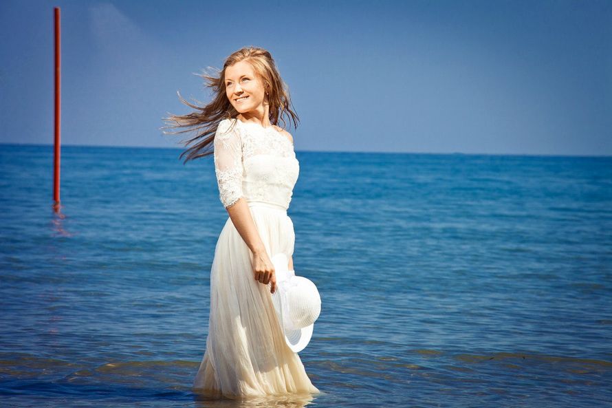 Невеста в белом длинном закрытом платье стоит в море по колено в воде  - фото 1076073 Angie