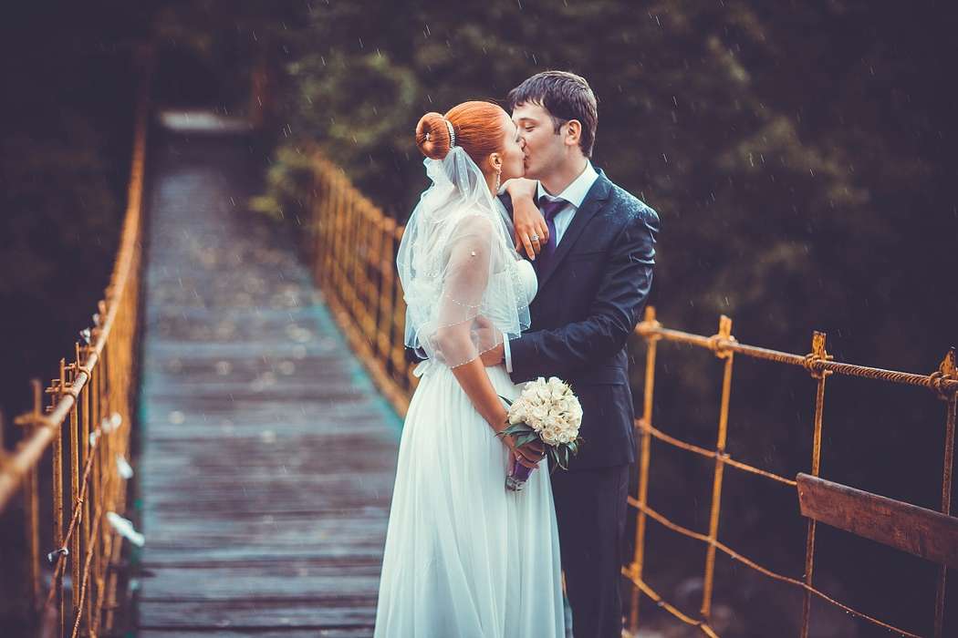 Жених и невеста, прислонившись друг к другу, стоят на мосту на фоне деревьев - фото 3069031 Фотограф Диана Сумская
