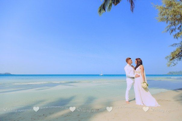 На песчаном побережье, на фоне лазурного океана стоят влюбленные и смотрят друг другу в глаза, жених в белом легком костюме - фото 2832699 Romantica - свадебное агентство в Таиланде