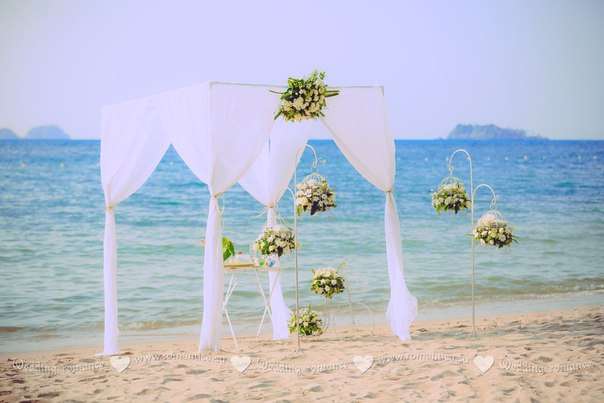 На пляже стоит белая арка и столик, вокруг висят белые цветы - фото 2832701 Romantica - свадебное агентство в Таиланде