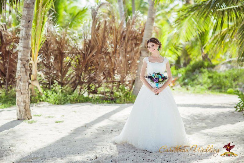 В тени пальм стоит невеста в белоснежном пышном платье, в руках у нее букет цветов - фото 3212119 Caribbean Wedding - свадьба в Доминикане