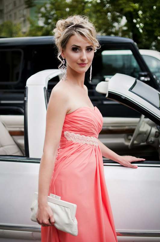 Подружка невесты в розовом открытом платье с драпировкой, завышенной талией и декором на ней, с белым клатчем возле кабриолета  - фото 1299803 Невеста01